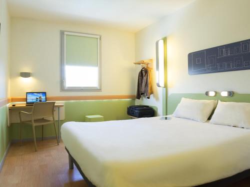 a hotel room with a large bed and a desk at Ibis Budget Valence Sud in Valence