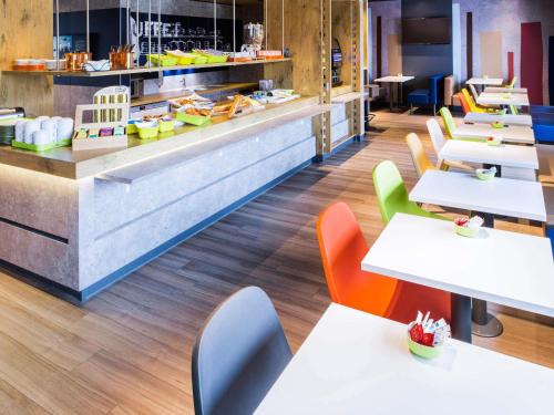 a restaurant with white tables and colorful chairs at Ibis Budget Valence Sud in Valence