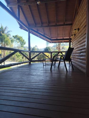 a porch with two chairs and a table on it at Refugio Poço do Cânion in Barracão