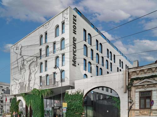 a white building with a sign on the side of it at Mercure Bucharest City Center in Bucharest
