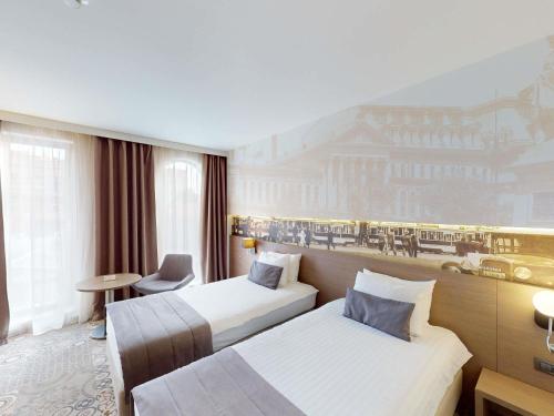 a hotel room with two beds and a mural at Mercure Bucharest City Center in Bucharest
