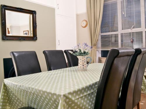 Una mesa de comedor con un jarrón de flores encima. en Chestney House, en Hunstanton