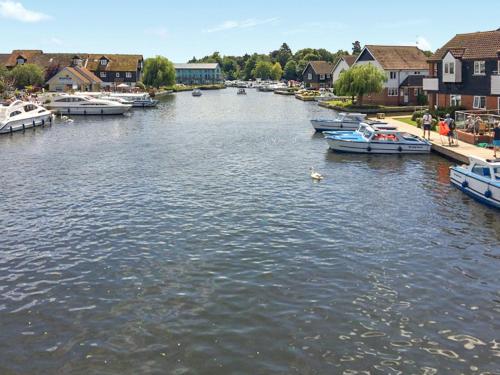 a river with boats docked in a town with houses at Blackfriars in Wroxham