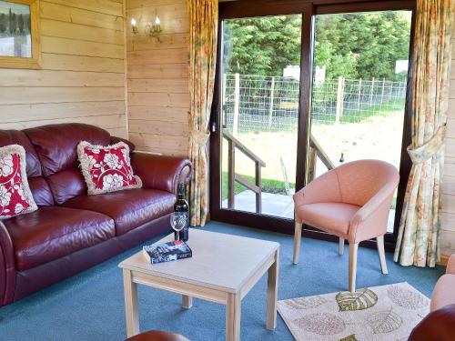 ein Wohnzimmer mit einer Ledercouch und einem Tisch in der Unterkunft Hartland Forest Golf & Leisure in Woolfardisworthy