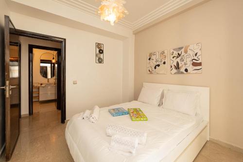 Un dormitorio con una cama blanca en una habitación. en Welcome to Tamaris Escape 2BR Sea & Vue Piscine, en Dar Mohammed Ould Haj Jilali