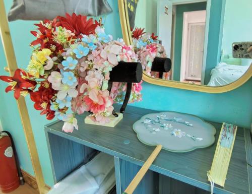 a dressing table with a mirror and flowers on it at 厦门哈哈虎客栈 in Xiamen