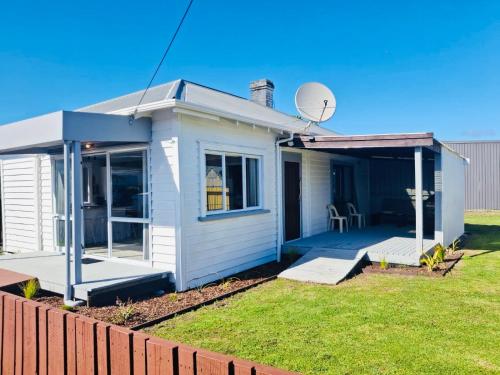 a small white house with a satellite at The cottage coghill in Whitianga