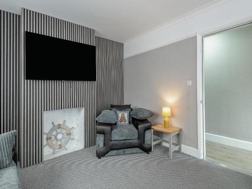 a living room with a chair and a flat screen tv at Sandy Lodge in Chapel Saint Leonards
