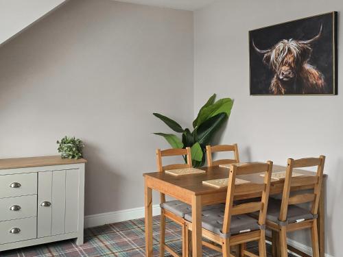 a dining room table and chairs with a picture of a cow at Holy Loch View in Strone