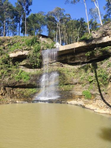a waterfall over a body of water at Refugio Poço do Cânion in Barracão