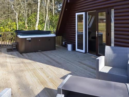 a hot tub on a deck next to a house at Squirrel Lodge in Otterburn