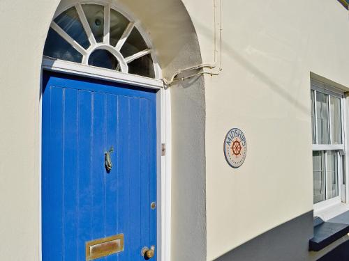 a blue door in a white wall with a window at Midships in Instow