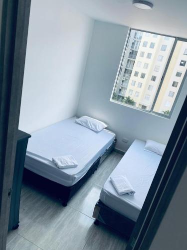 two beds in a small room with a window at Apartamiento Ricaurte -Colombia in Girardot