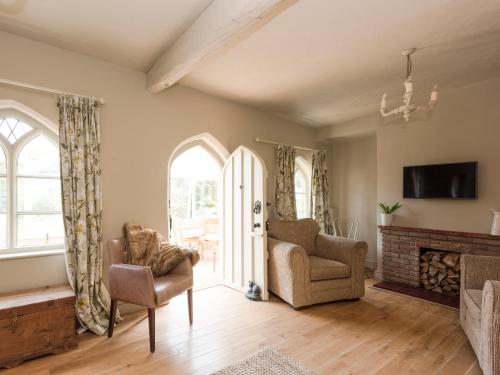 a living room with two chairs and a fireplace at Dell Cottage in Mundesley