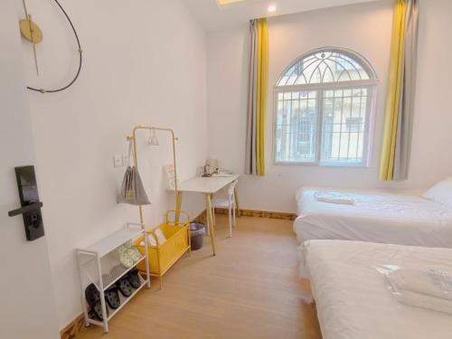 a room with two beds and a desk and a window at 厦门哈哈虎客栈 in Xiamen