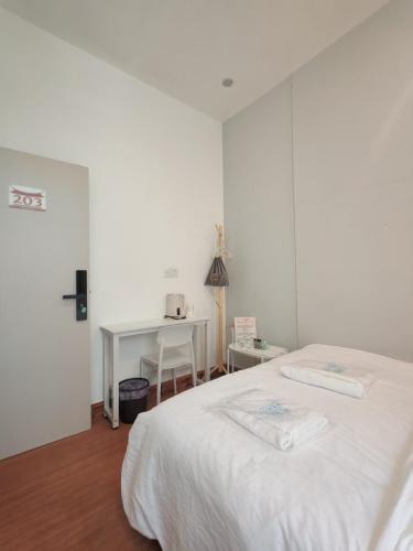 a white bedroom with a bed and a desk at 厦门哈哈虎客栈 in Xiamen