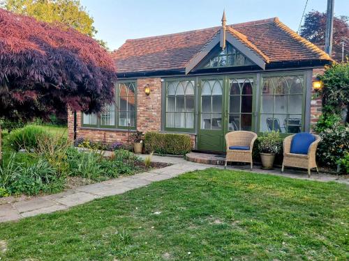 a house with a conservatory in a garden at The Little Cottage in Fittleworth