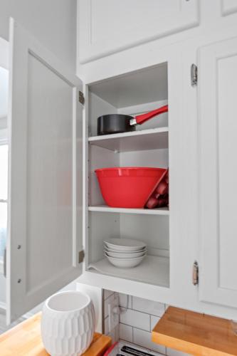a kitchen with white cabinets and a red bowl at Luxe Suite with Pool Table, King Bed, 3 TVs, & Free Parking in Cleveland
