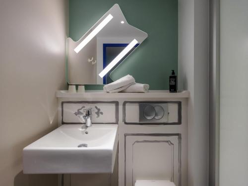 a bathroom with a sink and a arrow above a toilet at ibis budget Albertville in Gilly-sur-Isère