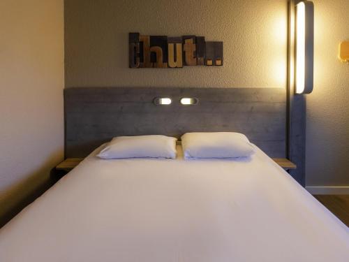 a bedroom with a large white bed with two pillows at ibis budget Albertville in Gilly-sur-Isère