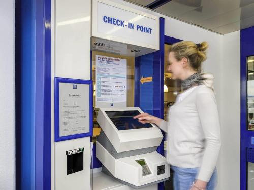 a woman is standing next to an atm machine at ibis budget Albertville in Gilly-sur-Isère