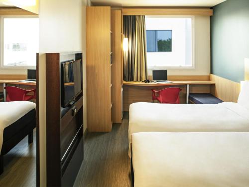 a hotel room with two beds and a desk at ibis Rio de Janeiro Parque Olimpico in Rio de Janeiro