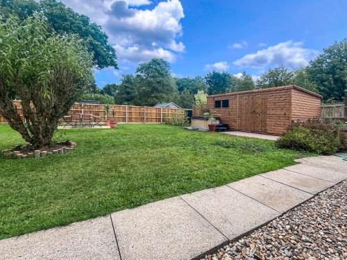 a backyard with a fence and a wooden shed at Dippers in Smallburgh