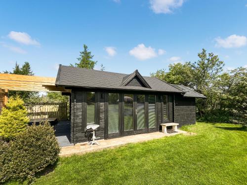 a black house with a bench in a yard at The Cabin in Dearham