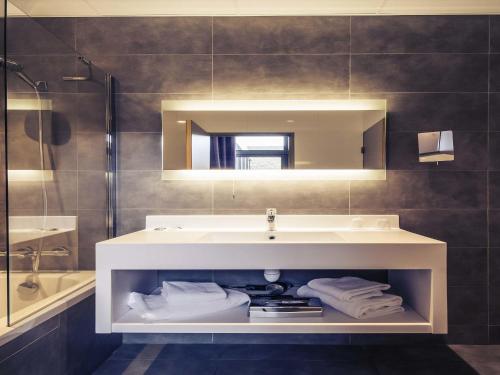 a bathroom with a sink and a mirror at Mercure Cherbourg Centre Port in Cherbourg en Cotentin