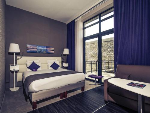 a hotel room with a bed and a balcony at Mercure Cherbourg Centre Port in Cherbourg en Cotentin