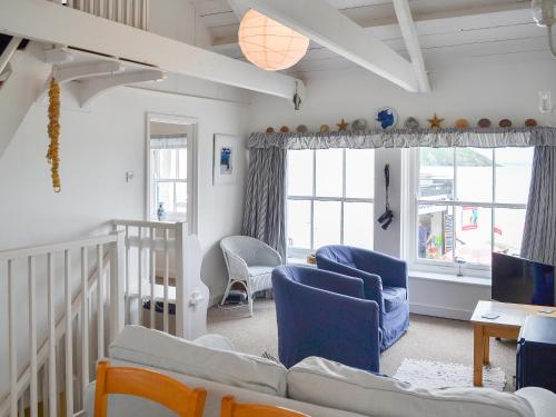 Una sala de estar con sillas azules y un sofá. en Beach Corner Cottage, en Gorran Haven