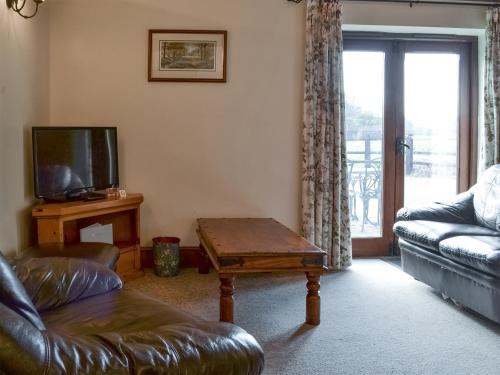 a living room with a couch and a tv and a table at Baileys Barn - Ukc3738 in Bawdeswell