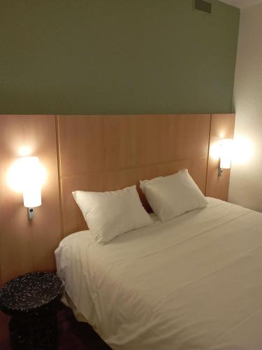 a bedroom with a white bed with two pillows at ibis les Etangs des Moines in Fourmies