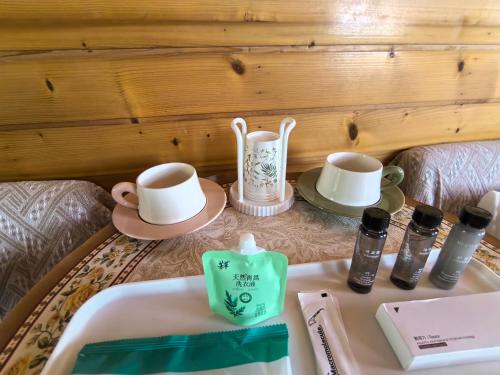 a coffee table with two cups and a tray with cosmetics at 厦门哈哈虎客栈 in Xiamen