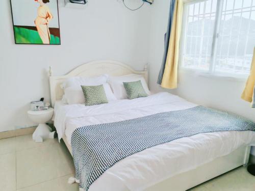 a bedroom with a white bed and a window at 厦门哈哈虎客栈 in Xiamen