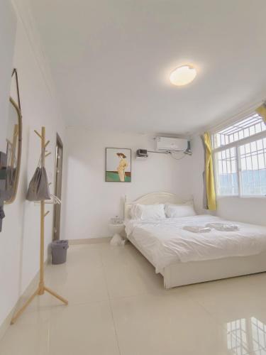 a white bedroom with a bed and a window at 厦门哈哈虎客栈 in Xiamen