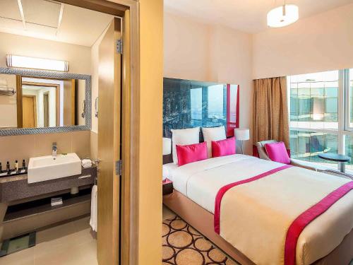 a hotel room with a large bed and a sink at Adagio Premium Dubai Al Barsha in Dubai