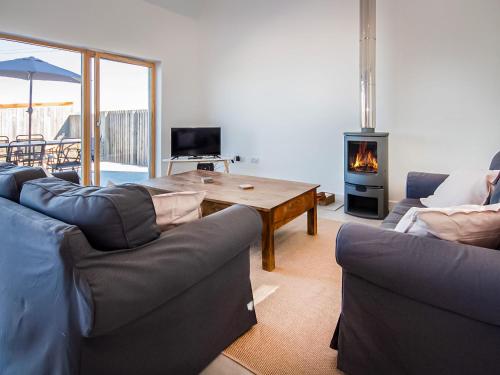 a living room with a couch and a table with a fireplace at Y Bwthyn in Culbokie
