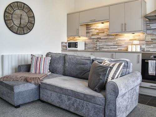 a couch in a living room with a clock on the wall at Headland View in Scarborough