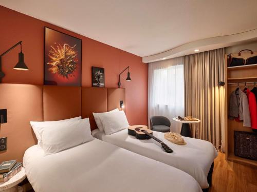 a hotel room with two beds and a chair at IBIS Port de plaisance in Caen