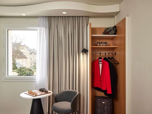 a room with a door with a red jacket and a chair at IBIS Port de plaisance in Caen