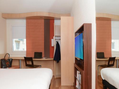 a bedroom with a bed and a tv and a desk at IBIS Port de plaisance in Caen