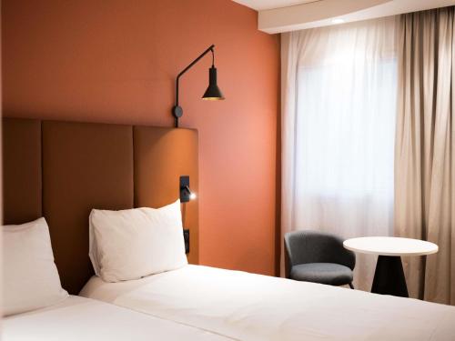 a hotel room with a bed and a chair and a window at IBIS Port de plaisance in Caen