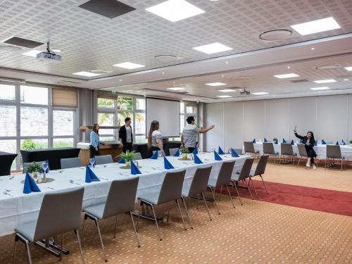 a group of people standing in a room with tables and chairs at IBIS Port de plaisance in Caen