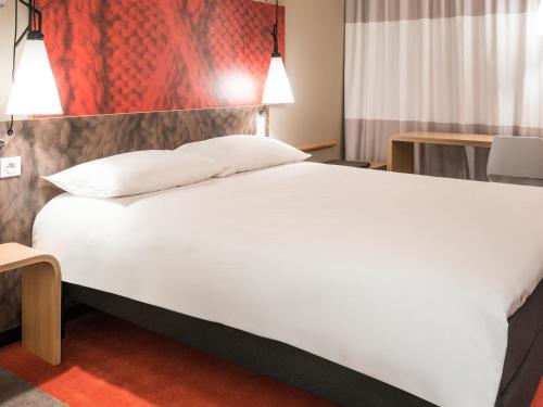 a large white bed in a hotel room at ibis Dole Sud Choisey in Dole