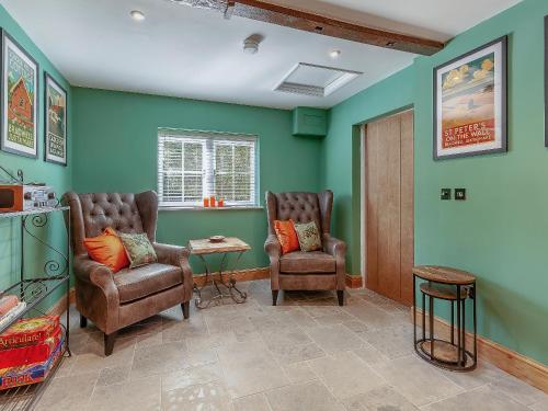 a living room with two chairs and a table at The School House Cottage in Bradwell on Sea