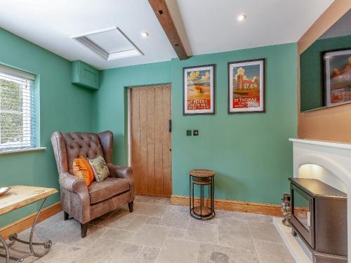 a living room with a chair and a tv at The School House Cottage in Bradwell on Sea