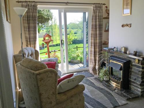 een woonkamer met een stoel en een open haard bij Rose Cottage in Cheriton Bishop