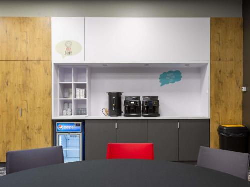a kitchen with a table and a red chair at ibis Warszawa Centrum in Warsaw