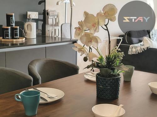 une table en bois avec un vase avec des fleurs dessus dans l'établissement Grand Medini Couple Stylish Netflix 100mbps BySTAY, à Nusajaya